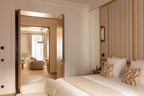 Ein Hotelzimmer mit einem großen Bett, einer Sitzecke mit einer Couch und Blick in ein weiteres Zimmer.