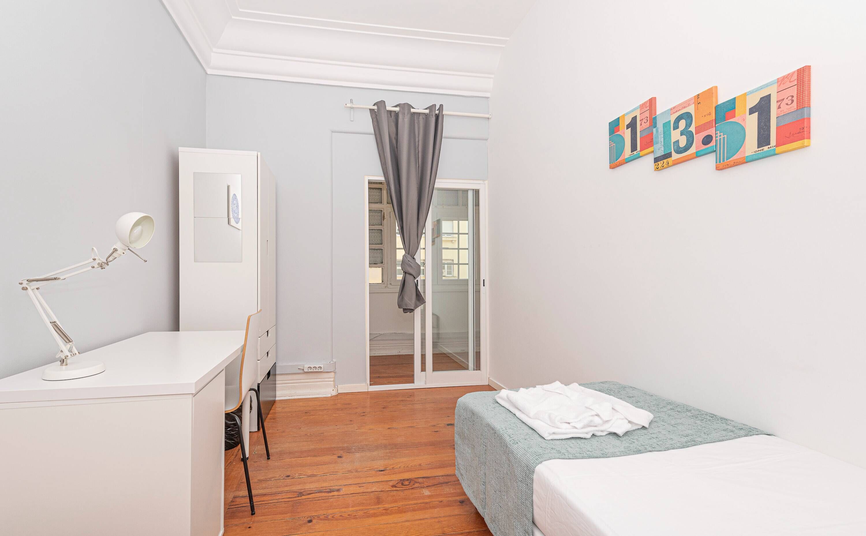 Une chambre avec un bureau, un lit, une armoire, un rideau et un mur orné de chiffres.