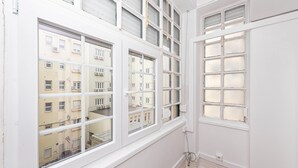 Una habitación con paredes blancas, suelo de madera y un ventanal de hojas múltiples.