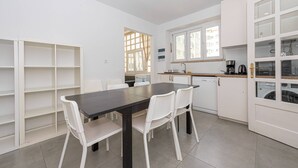 Una cocina moderna con armarios blancos, una mesa de comedor con sillas y una ventana con cortinas.