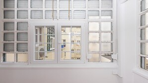 Habitación con un ventanal grande con una cuadrícula de paneles más pequeños, un equipo de aire acondicionado visible y vista a un edificio.