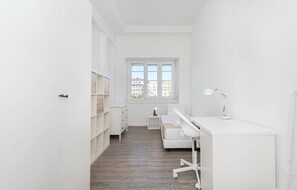 Een witte kamer met een bureau, stoel en een kastenwand.
