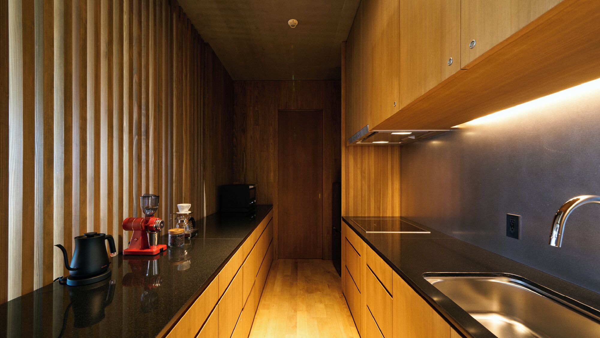 Una cocina moderna con armarios de madera, encimera negra y electrodomésticos de acero inoxidable.