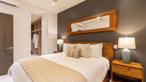Een slaapkamer met een bed, nachtkastjes, een spiegel en een kledingkast.