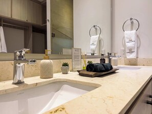 Et moderne badeværelse med vask, spejl, håndklædetørre og toiletartikler.