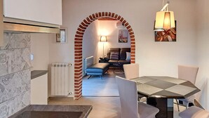 A dining area with a table and chairs, a brick archway, a radiator, and a hanging light fixture. - Gorgeous home in Nova Vas (Nova Vas)