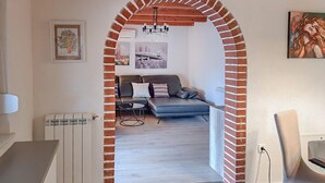 An interior space with a brick archway leading to a living area with a sofa, a coffee table, and artwork on the walls. - Gorgeous home in Nova Vas (Nova Vas)
