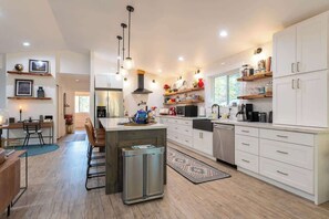 A modern kitchen with white cabinetry, a central island, and pendant lighting. - 5-acres, 2 Cabins, Hot Tub, Sauna, Game Rm, Trails (Grapeview)