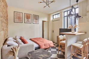 A cozy living area with a sofa, a coffee table, and a dining table with chairs. There are framed artworks on the wall, a chandelier, and a window with a view. - Apartement Center of Paris (Paris)