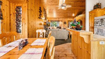 Un interior de madera con comedor, sofá y mostrador de cocina.