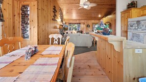 A wooden cabin interior with a dining area, kitchen, and a cozy living space. - Meandering moose (Big Bear Lake)