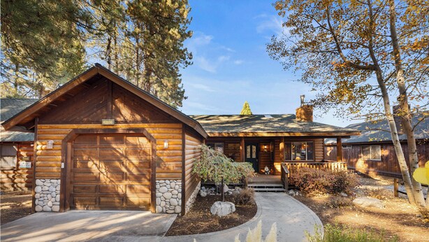 A log cabin with a stone foundation, a garage, and a well-maintained front yard with landscaping. - Meandering moose (Big Bear Lake)