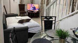 Ein Wohnzimmer mit Sofa, Fernseher, Treppe und Essbereich.