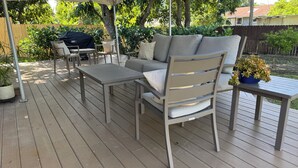 Une terrasse en bois aménagée avec du mobilier d’extérieur, notamment un canapé, des fauteuils et une table.