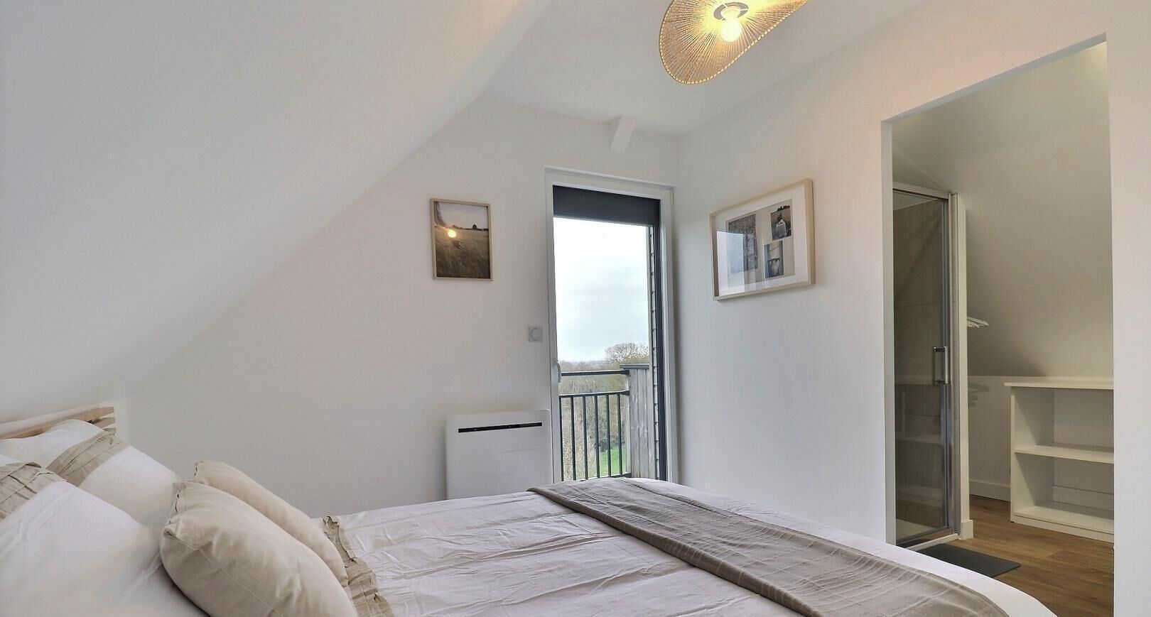 A bedroom with a bed, a radiator, a door leading to a balcony, and a white shelf unit.