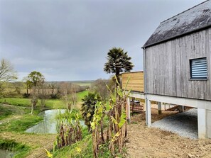 A rustic wooden building with a balcony overlooking a pond and greenery. - L'Orée du Mont - SOUGEAL (SOUGEAL)