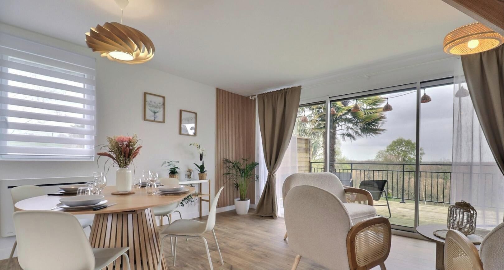 Un coin repas avec une table en bois, des chaises blanches et un balcon offrant une vue agréable.
