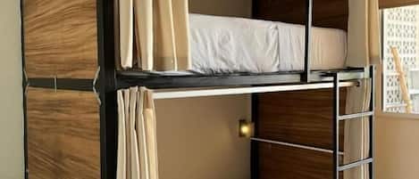 Una cama litera con estructura de madera, una escalera y cortinas.