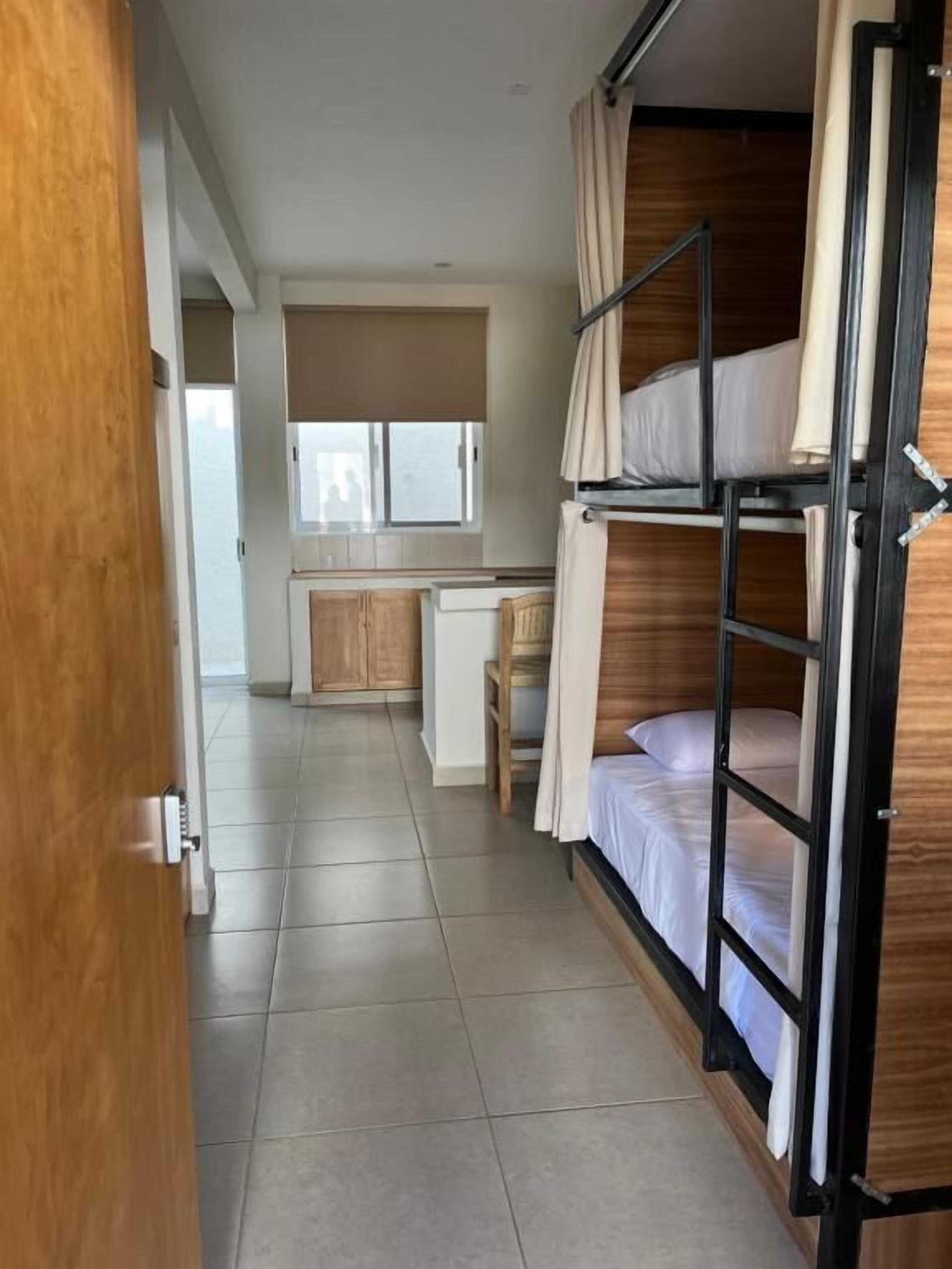 Habitación con literas, un escritorio, una silla, una ventana y una puerta.