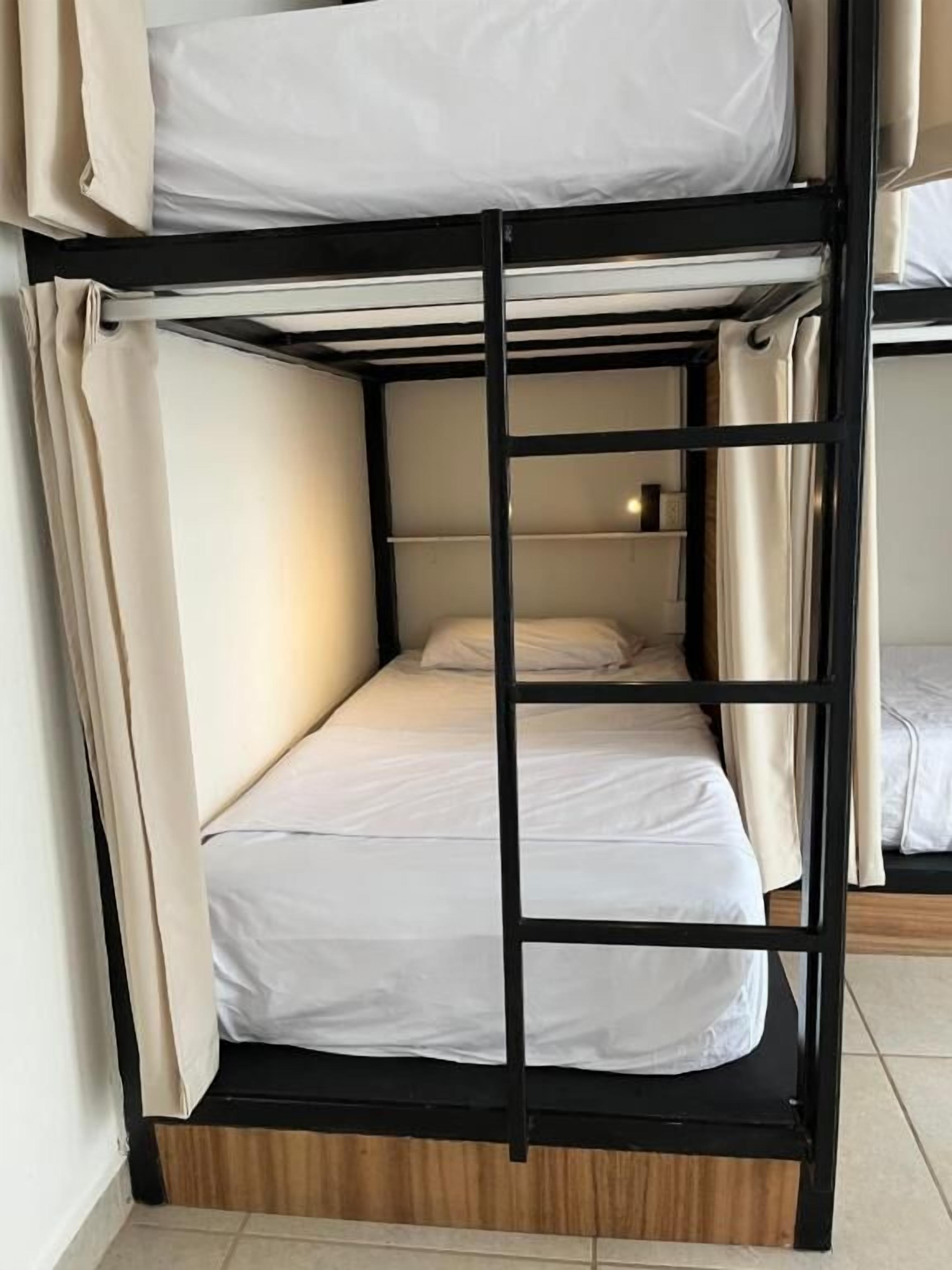 A bunk bed with a ladder, white bedding, and curtains.