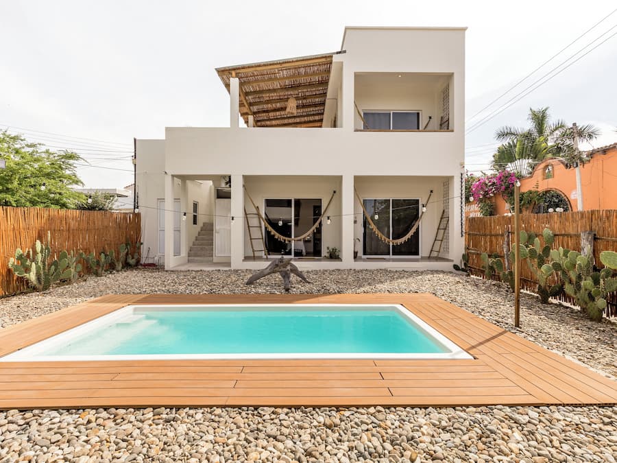 A modern two-story house with a swimming pool, wooden deck, and a cactus garden.