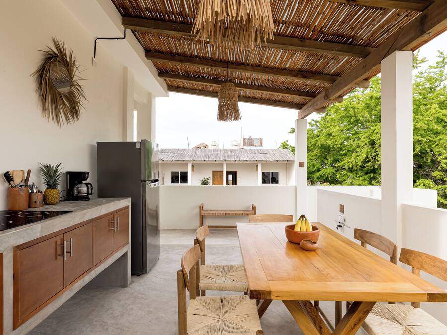 Una cocina con una mesa y sillas de madera, un refrigerador y una lámpara colgante.
