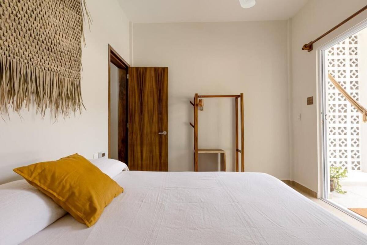 Une chambre à coucher avec un lit, une porte en bois, une chaise en bois et une vue par la fenêtre.