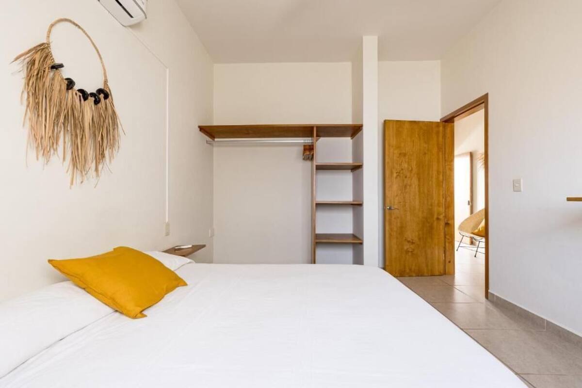 Une chambre à coucher avec un lit, une armoire en bois et une porte donnant sur une autre pièce.