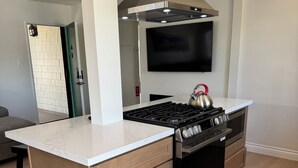 A modern kitchen with a central island, stainless steel appliances, and a large range hood.