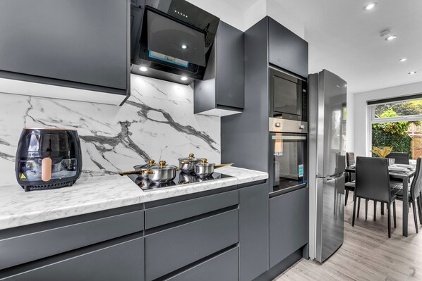 A modern kitchen with a marble countertop, stainless steel appliances, and a dining area with a view.