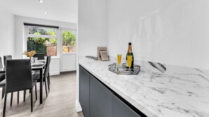 Een moderne keuken met een marmeren aanrecht, zwarte stoelen en een eettafel.