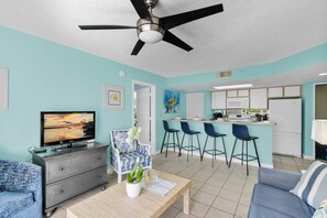A modern living room with a TV, sofa, coffee table, and a ceiling fan.