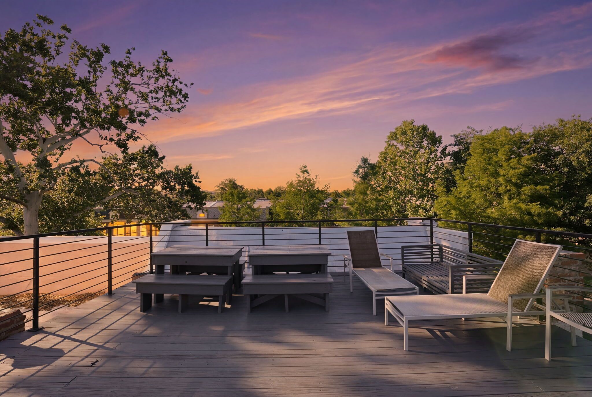 Una terraza al aire libre con asientos y vistas a árboles y una puesta de sol.