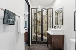 Un baño moderno con cabina de ducha de vidrio, un lavamanos blanco y un espejo grande.