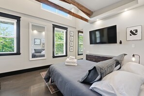Un dormitorio moderno con una cama grande, un televisor de pantalla plana y cuadros enmarcados en la pared.