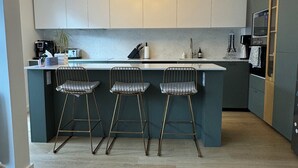 A modern kitchen with a central island, bar stools, and a unique light fixture. - Modern, family-friendly Parisian apartment (Paris)