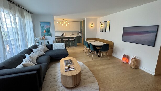 A modern living room with a sofa, coffee table, and dining area with chairs. - Modern, family-friendly Parisian apartment (Paris)