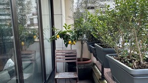 A wooden bench outside a building with a potted plant and a window. - Modern, family-friendly Parisian apartment (Paris)