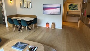 A modern living room with a dining area, a bookshelf, and a painting on the wall. - Modern, family-friendly Parisian apartment (Paris)