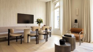 Ein modernes Wohnzimmer mit Sofa, Esstisch, Stühlen, einem Fernseher, einer Vase mit Blumen und einer Statue.