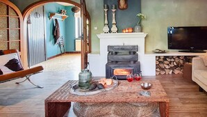 A living room with a fireplace, a television, and a coffee table with decorative items. - Charming Garden Holiday Home for 6 (Weris)