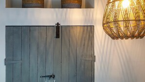 A rustic door with a metal latch, a woven basket on the wall, and a hanging light fixture. - Charming Garden Holiday Home for 6 (Weris)