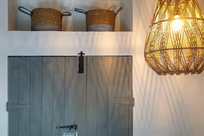 A rustic door with a metal latch, a woven basket on the wall, and a hanging light fixture. - Charming Garden Holiday Home for 6 (Weris)