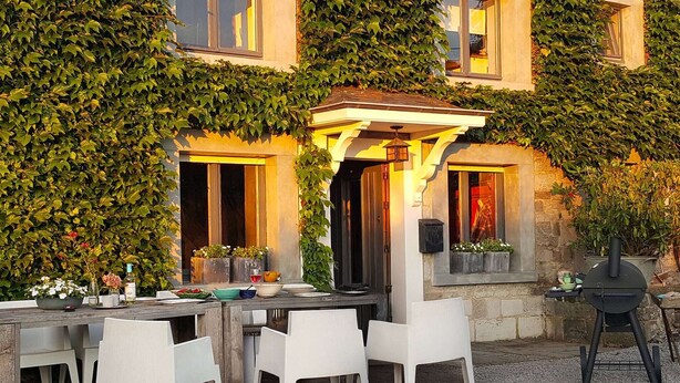 An outdoor dining area with a table and chairs, a grill, and a building covered in ivy. - Charming Garden Holiday Home for 6 (Weris)