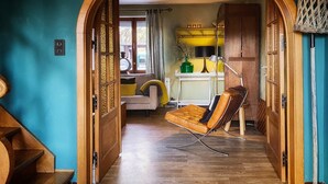 A hallway with a wooden chair, a sofa, and a kitchen area with a stove and cabinets. - Charming Garden Holiday Home for 6 (Weris)