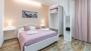 A bedroom with a bed, bedside lamps, a painting, a wardrobe, and a curtain. - 'Beb della Stazione - Rosa' Room with Shared Terrace, Wi-Fi and Air Conditioning (Pachino)