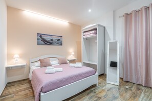 A bedroom with a bed, bedside lamps, a painting, a wardrobe, and a curtain. - 'Beb della Stazione - Rosa' Room with Shared Terrace, Wi-Fi and Air Conditioning (Pachino)