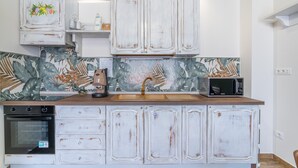 A kitchen with white cabinets, a microwave, a sink, and a stove. - 'Beb della Stazione - Rosa' Room with Shared Terrace, Wi-Fi and Air Conditioning (Pachino)