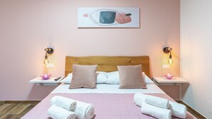 Ein Hotelzimmer mit einem hölzernen Kopfteil, zwei Nachttischen mit Lampen, einem Bett mit rosa Bettwäsche und einem Gemälde darüber.