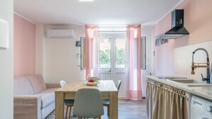 Ein kompakter Wohnraum mit Küchenzeile, Essbereich und Sofa.